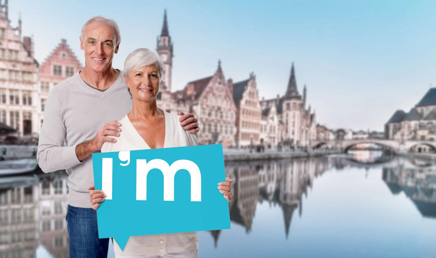 Gepensioneerd koppel staat in Gent met IntelliGent Mobiel logo in zijn handen